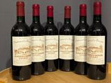 four bottles of red wine sitting on top of a wooden barrel