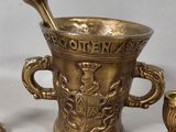 a gold cup with a spoon in it next to two other cups