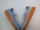 une paire de baskets Adidas bleues et orange sur fond blanc