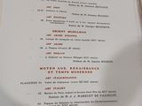 un menu posé sur une table où se trouve un verre de vin