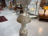 un vase en argent posé sur un socle dans une pièce