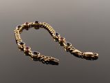 a close up of a gold bracelet with black and red stones