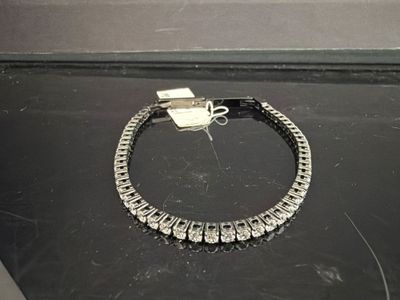 une photo d'un bracelet en diamants posé sur une surface noire