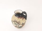 a small vase with a black handle on a white surface