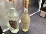 two bottles of alcohol sitting on a counter next to each other