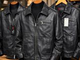 three black leather jackets hanging on a rack in a clothing store