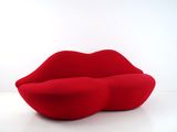 une image représentant un canapé rouge sur lequel est posée une lèvre rouge
