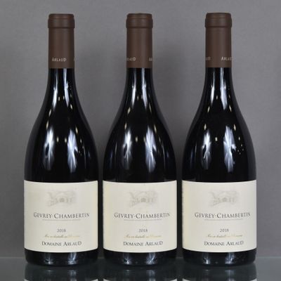 three bottles of wine are lined up on a glass table