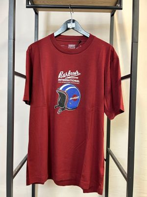 un t-shirt rouge représentant un casque, suspendu à un cintre devant un mur blanc