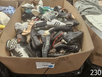 plusieurs paires de chaussures dans une boîte en carton posée sur le sol