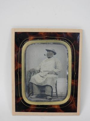 an old photo of a woman sitting in a chair with a hat on