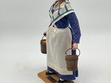 figurine of a woman with buckets on a wooden stand