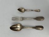 three silver spoons and a fork on a white surface