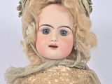 an antique doll with blonde hair and blue eyes wearing a brown dress