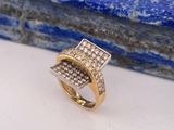 un gros plan d'une bague en or et diamants posée sur une pierre bleue