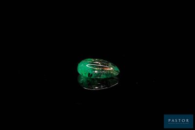 an image of a green stone in the dark on a black surface