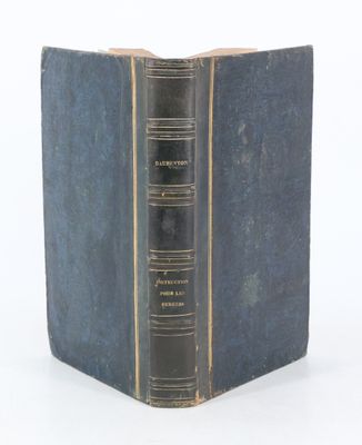 un vieux livre à la couverture bleue posé sur une surface blanche