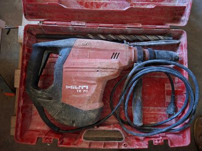une boîte rouge contenant une perceuse et une cordelette