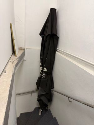 un parapluie noir accroché au mur près d'un escalier