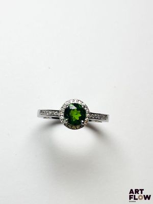 gros plan d'une bague avec une pierre verte entourée de diamants