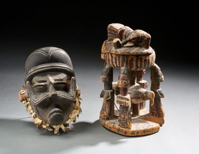 paire de masques africains sculptés en bois sur socle, dont l'un porte un chapeau et l'autre un visage