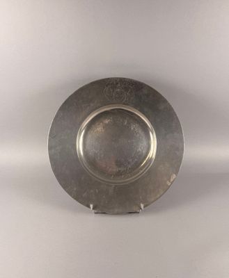 a silver plate on a stand on a white surface