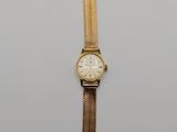a close up of a gold watch on a white surface