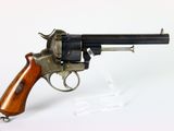un vieux revolver avec une poignée en bois sur une surface blanche