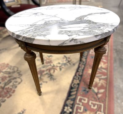 une table au plateau en marbre posée sur un tapis au sol