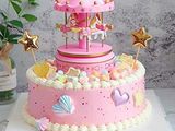 a pink cake that has a carousel on top of it