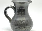 un pichet noir avec une inscription sur fond blanc