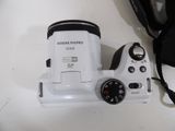 a white camera sitting on a table next to a black bag
