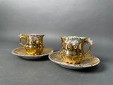 two cups and saucers are sitting on a plate on a gray surface