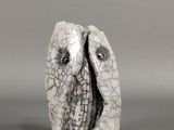 un gros plan sur une sculpture représentant deux oiseaux posés sur une surface grise