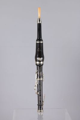 a close up of a black and silver clarinet on a clear surface