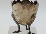 a silver vase that has a bird on it