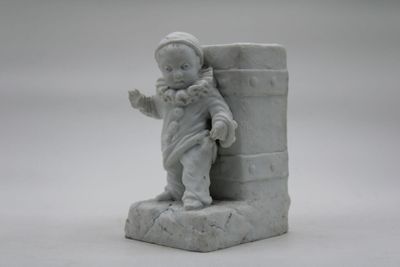 a small statue of a little boy holding a book
