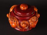 a red jar with a wooden lid on a black surface