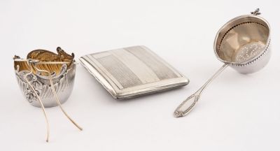 une tasse, une cuillère et un repose-cuillère en argent posés sur une surface blanche