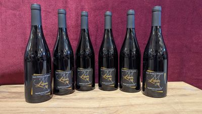 six bottles of wine are lined up on a wooden table