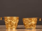 une paire de vases plaqués or posés sur une table en bois, sur fond noir