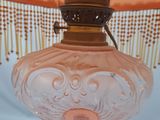 a pink glass lamp that is on a table