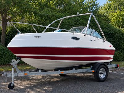 a white and red boat on a trailer in a parking lot
