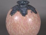 un vase rose et noir posé sur une surface grise