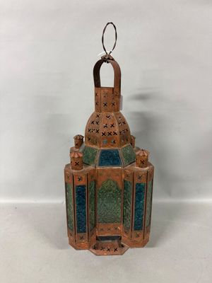 a small copper colored lantern with a green and blue glass inside