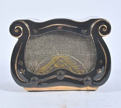 une radio vintage noire et dorée posée sur une table blanche