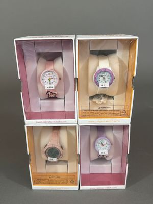 trois boîtes contenant chacune quatre montres différentes, posées sur une table