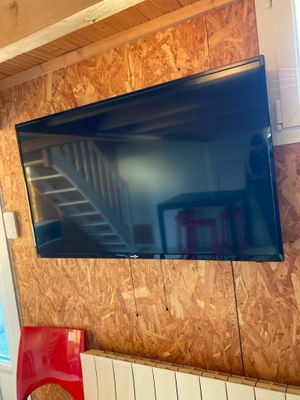 une télévision à écran plat accrochée au mur au-dessus d'un fauteuil rouge