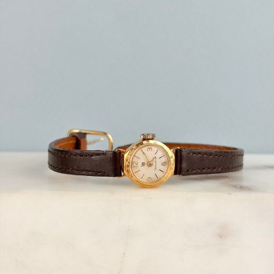 une image représentant une montre posée sur une surface en marbre, sur fond bleu