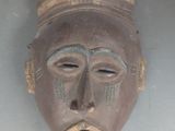 un masque en bois avec un visage brun et un chapeau sur la tête
